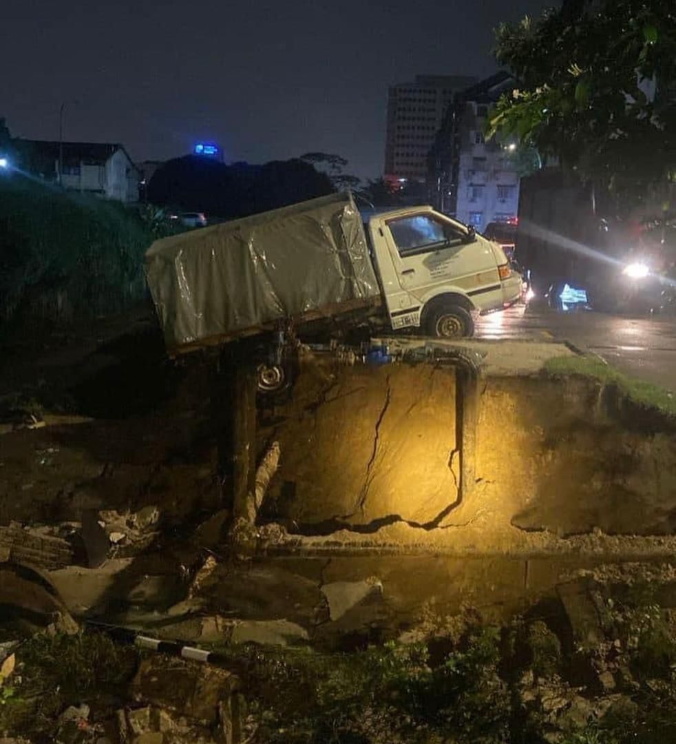 Prolonged heavy rain causes riverbank to collapse, damaging two vehicles