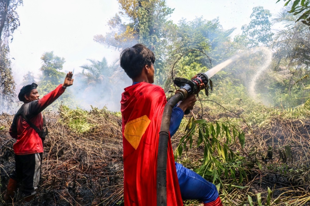 On Borneo’s scorched peatland, a teen volunteer in a Superman cape becomes an unlikely symbol of hope